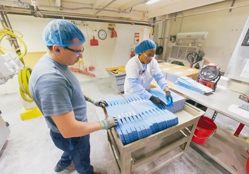 Two packaging technicians prepare product bags for the automated sugar filling machines.