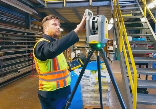 A surveyor in a high-visibility vest operates a laser scanner on a tripod inside an industrial facility, capturing spatial data.